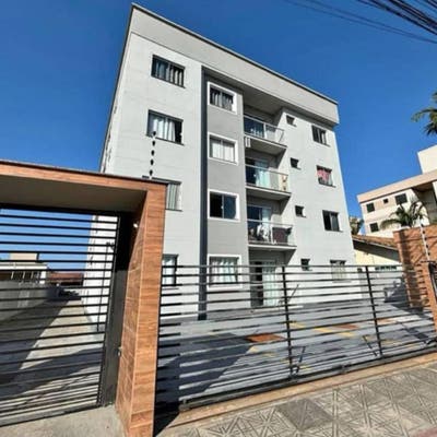 Edifício residencial moderno com fachada em tom cinza claro e varanda.