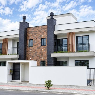 Prédio residencial com fachada moderna, combinação de branco, preto e tijolos.