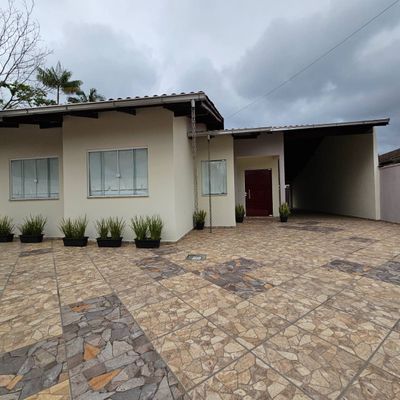 Fachada de casa com portão de entrada e plantas no jardim.