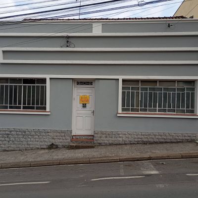 fachada de casa com paredes cinza, janelas de grades brancas