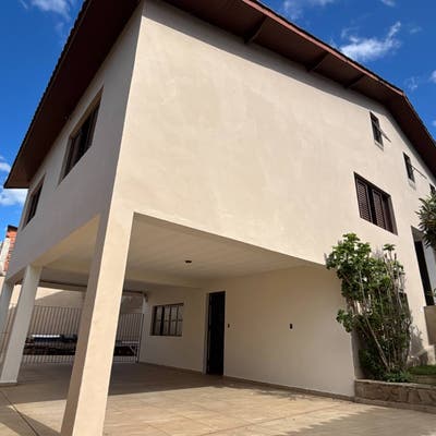 Fachada de casa moderna com acabamento em tinta clara e jardim frontal