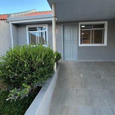 Fachada de casa com porta e janelas, área de varanda coberta, jardim