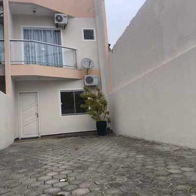 Fachada de residência com parede branca, porta e janela de vidro.