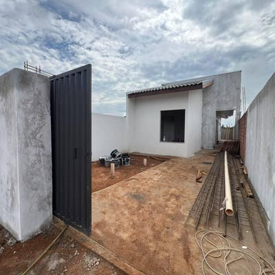 Pátio externo em construção com paredes brancas e chão de terra batida