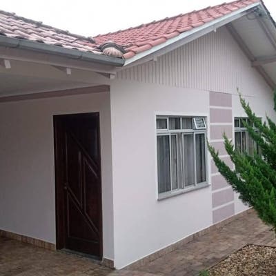 Casa com acabamento em reboco branco e telhado de cerâmica.