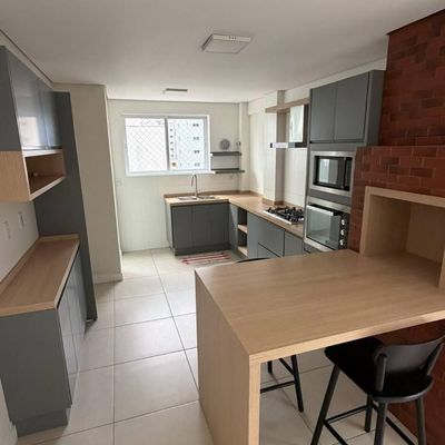 Cozinha moderna com armários cinza, bancada de madeira e parede de tijolos.